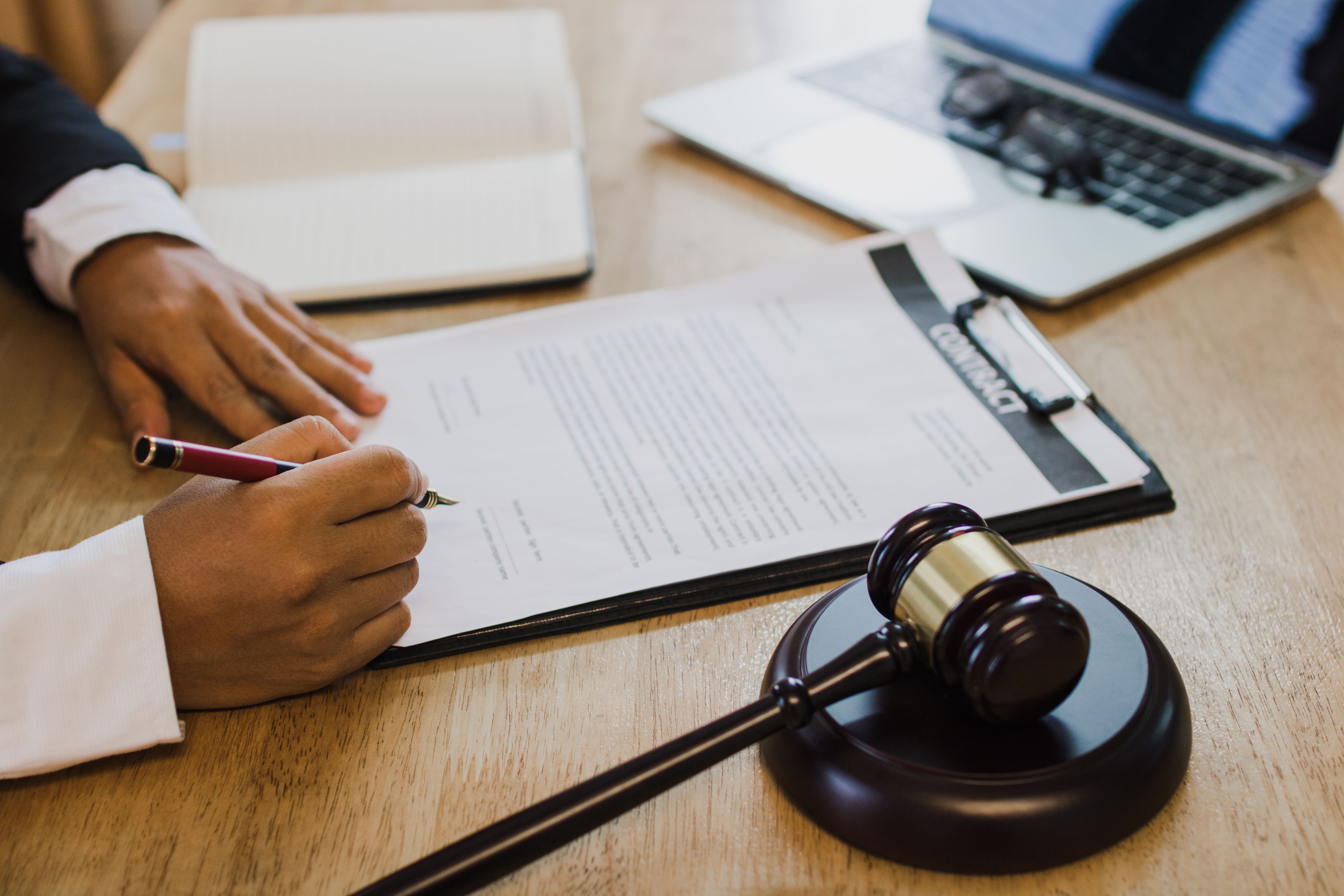 Someone signing a document next to a gavel